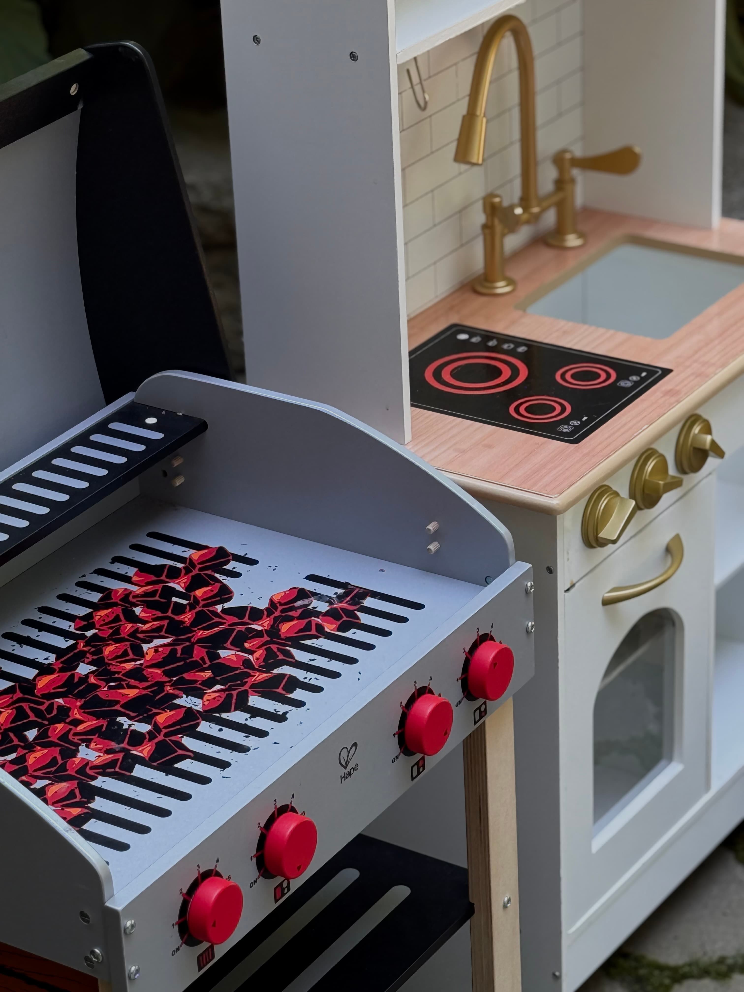 Luxury pretend play kitchen and grill station with gold fixtures at kids event setup